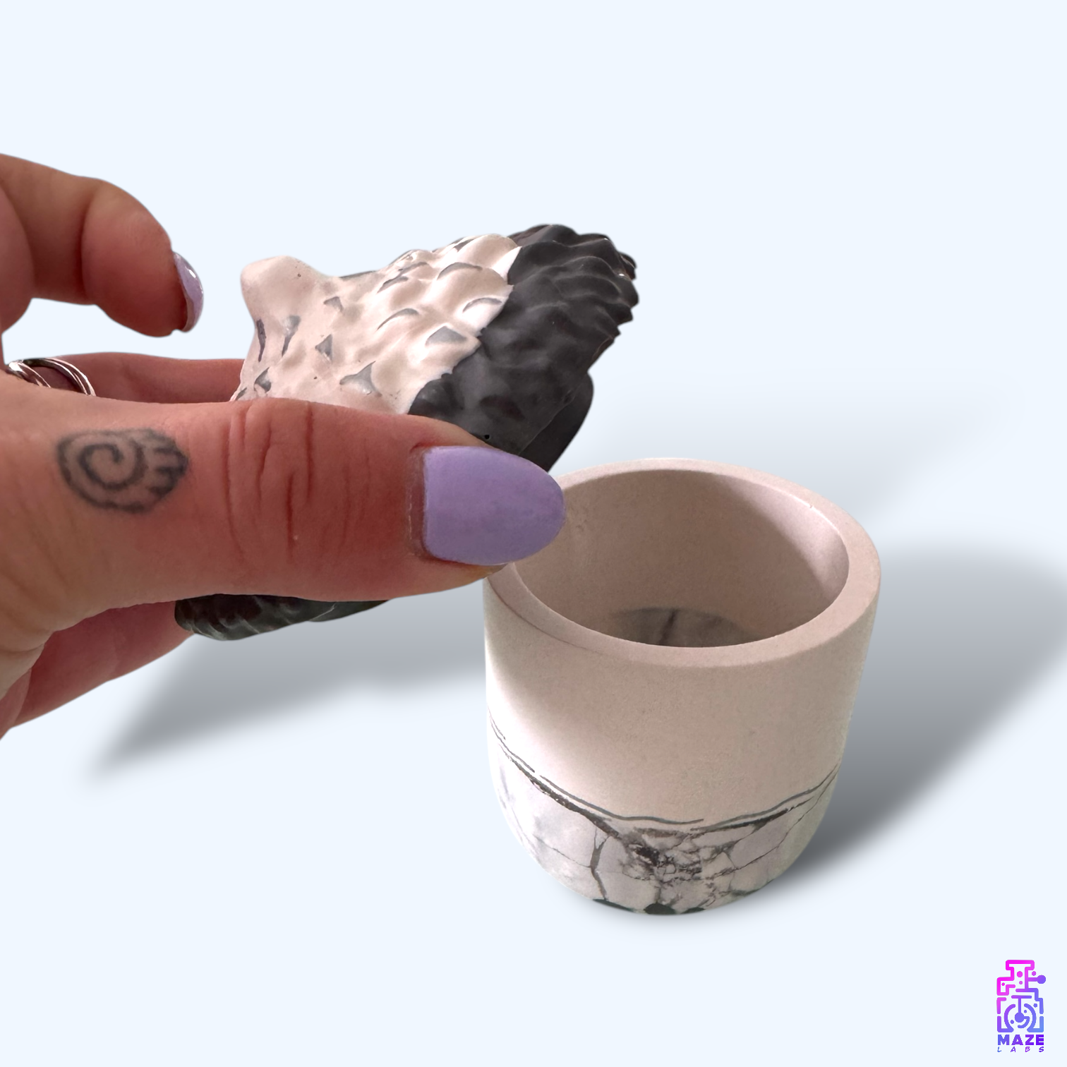 Hand holding the NOKT jar lid, showcasing its size and sculptural lid design.